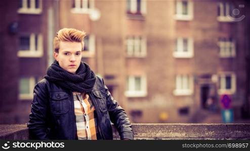 Street fashion. Young fashionable man guy with stylish haircut casual clothes posing outdoor on cityspace background. Aged tone