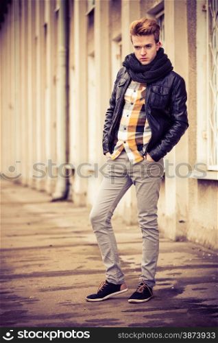 Street fashion. Young fashionable man in full length guy with stylish haircut casual clothes posing outdoor on cityspace background. Aged tone