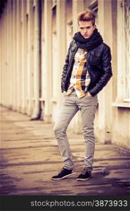 Street fashion. Young fashionable man in full length guy with stylish haircut casual clothes posing outdoor on cityspace background. Aged tone