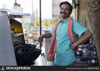 Street food vendor looking at camera with smile while making food at a stall