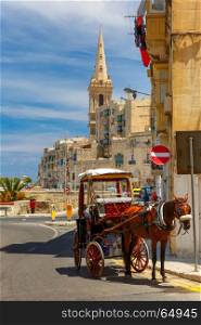Street in old town of Valletta, Malta. Horse carriage on the street of old town and St. Paul's Anglican Pro-Cathedral in Valletta, Malta