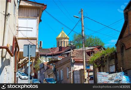 Street in the Tbilisi slum. Dome of Sameba cathedral on the background. Georgia