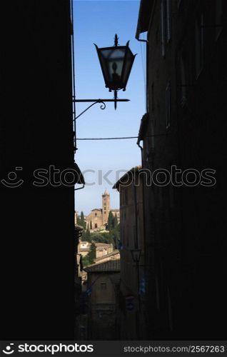 Street lamp and Siena buildings seen through darkened alley.