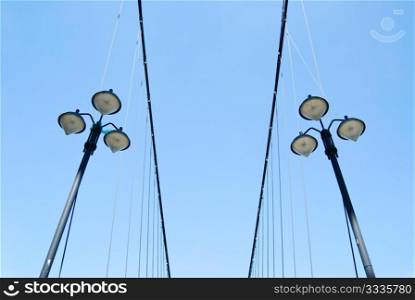 Street lamps under blue sky on the side of suspending bridge