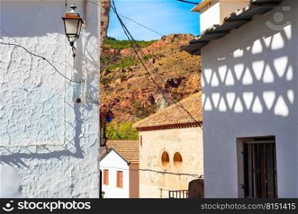 Street of an old mountain village in sunshine, shadows on wall, Cartagena, Spain