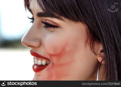 street portrait of beautiful young Caucasian brown haired girl with smeared lipstick on her face