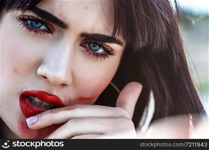 street portrait of beautiful young Caucasian brown haired girl with smeared lipstick on her face