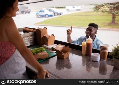 street sale and people concept - happy african american young man ordering wok at food truck. african american man ordering wok at food truck
