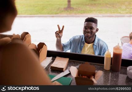 street sale and people concept - happy african american young man ordering wok at food truck. african american man ordering wok at food truck