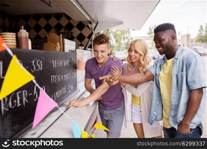 street sale and people concept - happy customers or friends choosing menu at food truck. customers or friends choosing menu at food truck