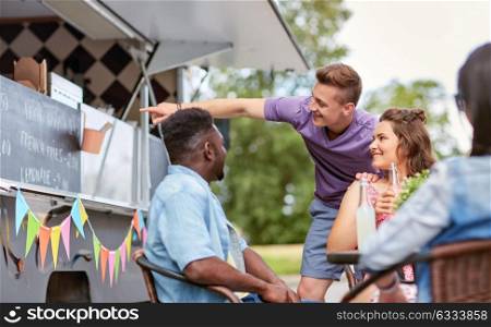 street sale and people concept - happy customers or friends looking at billboard at food truck. happy customers or friends at food truck