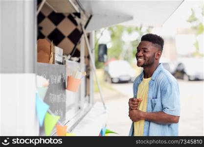street sale and people concept - happy smiling male customer looking at billboard at food truck. male customer looking at billboard at food truck