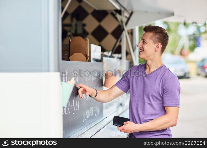 street sale and people concept - happy young male customer with wallet making order at food truck. male customer with wallet at food truck