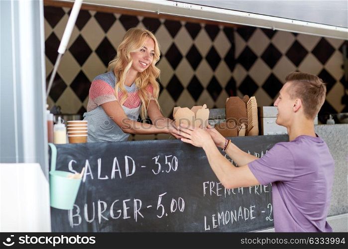 street sale and people concept - happy young saleswoman at food truck serving male customer. saleswoman at food truck serving male customer