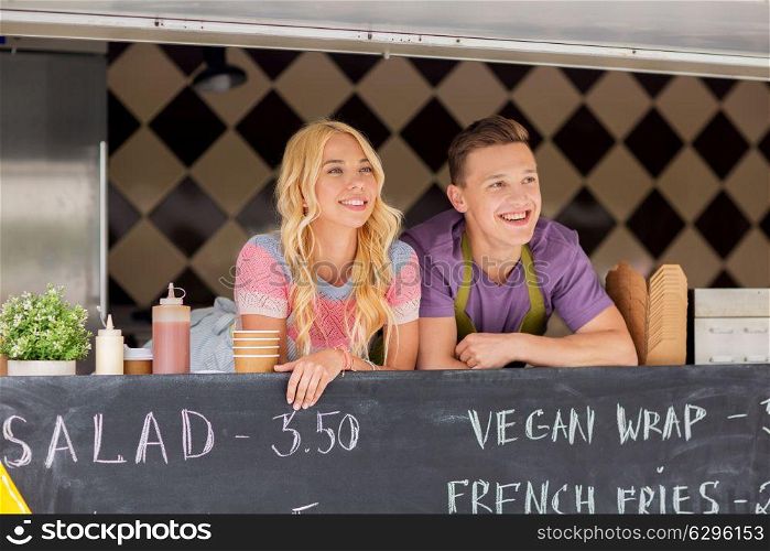 street sale and people concept - happy young sellers at food truck. happy young sellers at food truck