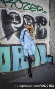 Street Style photo shoot of beautiful fashion blonde woman posing against graffiti wall