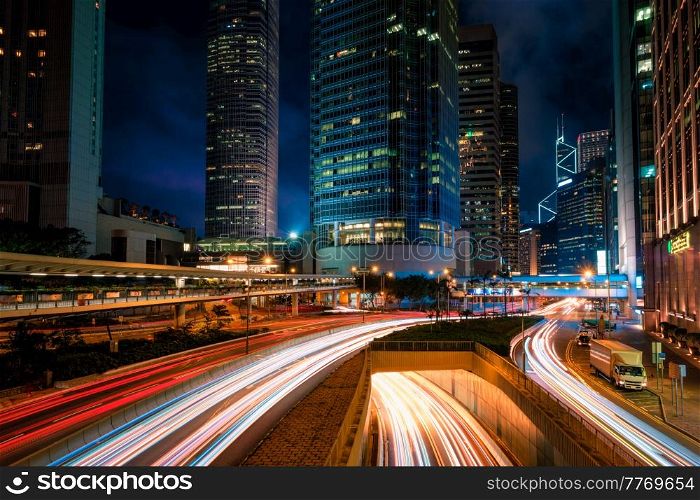 Street traffic in Hong Kong at night. Office skyscraper buildings and busy traffic on highway road with blurred cars light trails. Hong Kong, China. Street traffic in Hong Kong at night