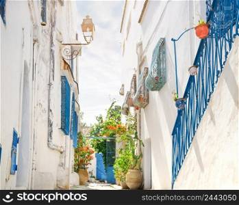 Street with white and blue houses under the bright sun.. The most popular tourist city of Tunisia. Sidi Bou Said, Tunisia. Street with white and blue houses under bright sun