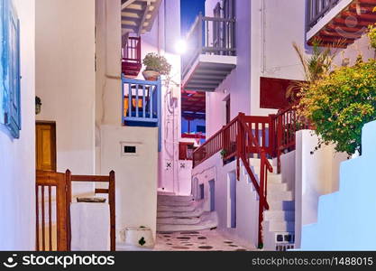 Street with white small houses with balconies in Mykonos town at night, Greece