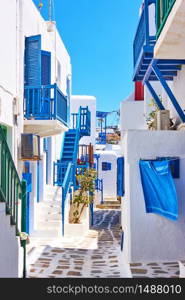 Street with white small houses with blue balconies in Mykonos island, Greece. Greek cityscape