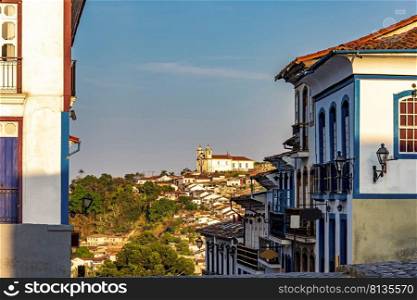 Streets and houses in the historic city of Ouro Preto in Minas Gerais with a church on top of the hill in the background.. Streets and houses in the historic city of Ouro Preto