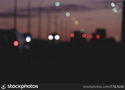 Streets in urban night with silhouettes of cars with defocused head and tail lights. Blurred Streets in urban night pink sky