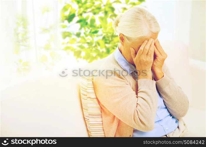 stress, age and people concept - senior woman suffering from headache or grief over window with green natural background. senior woman suffering from headache or grief. senior woman suffering from headache or grief