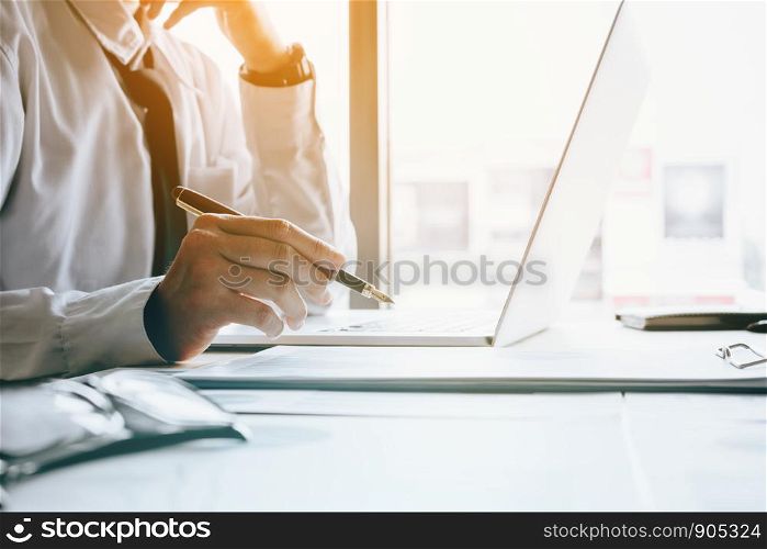 Stress businessman at office room holding pen pointing summary report graph and analyze with using laptop for searching information data.