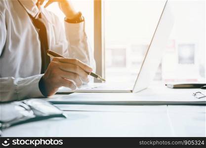Stress businessman at office room holding pen pointing summary report graph and analyze with using laptop for searching information data.