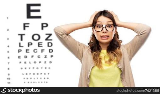 stress, education and school concept - asian woman or student in glasses fixed by tape holding to her head over eye test chart background. stressed woman in glasses over eye test chart