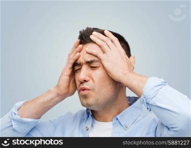 stress, headache, health care and people concept - unhappy man with closed eyes touching his forehead over gray background