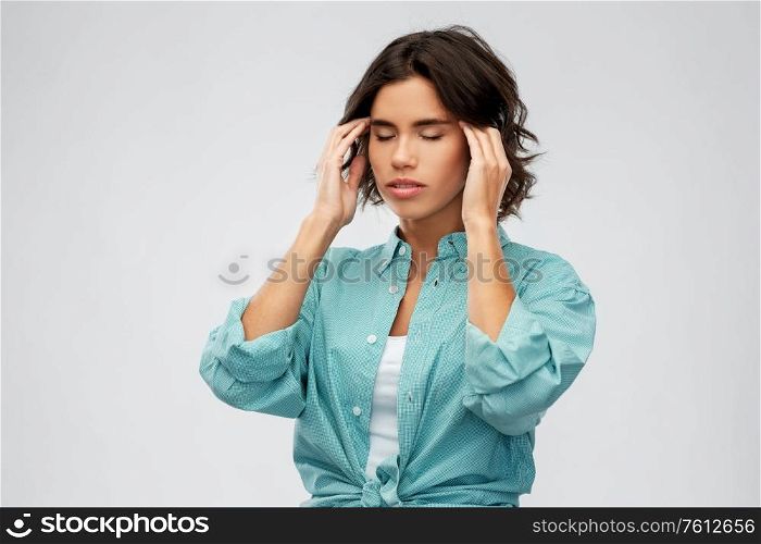 stress, health and people concept - young woman having headache holding to her head over grey background. woman having headache holding to her head