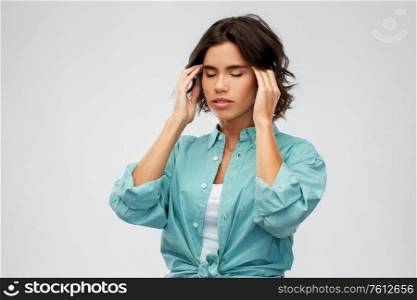 stress, health and people concept - young woman having headache holding to her head over grey background. woman having headache holding to her head