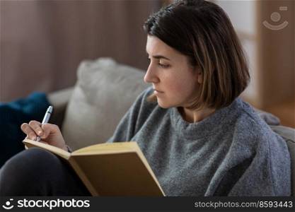 stress, mental health and depression concept - sad crying woman with diary sitting on sofa at home. crying woman with diary sitting on sofa at home