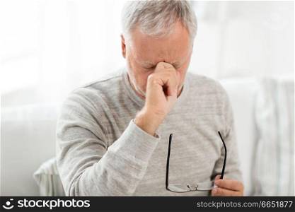 stress, old age and people concept - close up of senior man with glasses having headache and massaging nose bridge. senior man with having headache