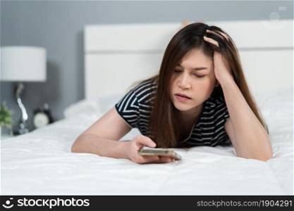 stress woman using smartphone on a bed