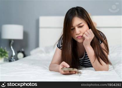 stress woman using smartphone on a bed