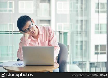 Stressed Asian businessman using laptop in living room