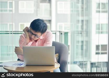 Stressed Asian businessman using laptop in living room