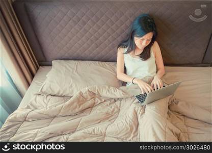 Stressed Asian woman using a laptop on bed in bedroom