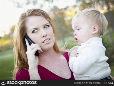 Stressed Attractive Woman Using Cell Phone with Child in Arms.