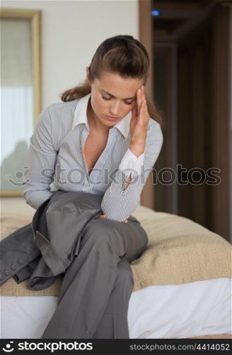 Stressed business woman sitting on bed in hotel room