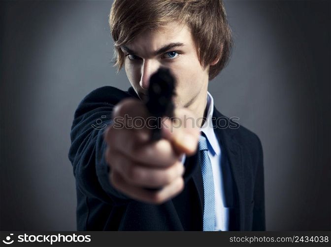 Stressed businessman holding and pointing a gun to the camera