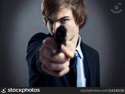 Stressed businessman holding and pointing a gun to the camera