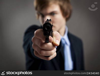 Stressed businessman holding and pointing a gun to the camera