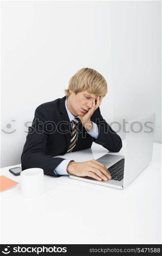 Stressed businessman using laptop at desk in office