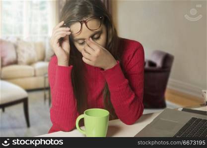 Stressed businesswoman at laptop with head in hands