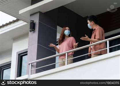 stressed couple wearing a face mask and quarantine in balcony of the home, coronavirus (covid-19) pandemic concept