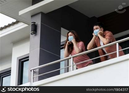 stressed couple wearing a face mask and quarantine in balcony of the home, coronavirus (covid-19) pandemic concept