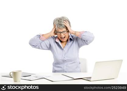 Stressed elderly woman working in the office with a laptop